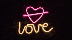 Bright luminous digital neon sign for a store or card beautiful shiny with a love heart pierced by cupid arrow. Glowing amour shape symbol passion in vivid colors. Valentines day concept.
