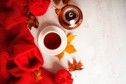 Autumn composition. A cup of tea and teapot, red sweater, autumn leaves. Flat lay, top view, copy space. 