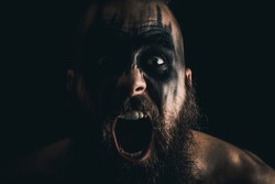 Portrait of a Viking warrior with black war paint, screaming with rage and anger