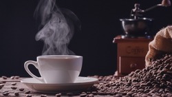 Natural steamed coffee smoke from a coffee cup, hot drink. Close-up hot coffee mug with realistic nature steam raising smoke with vintage grinder on dark background. Food and Drink Concepts
