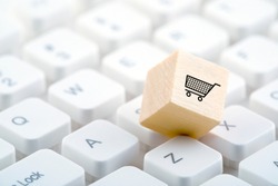 Wooden block with shopping cart graphic on computer keyboard. Online shopping concept. 