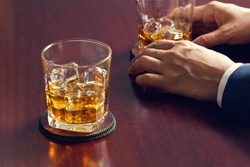 
 Glasses of whiskey in businessman's hands on wooden table background