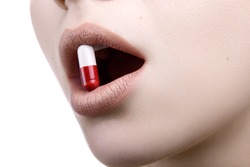 Close up of a face with the red white pill medicine in her mouth 