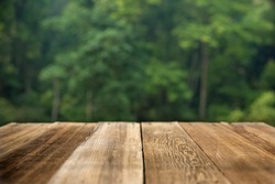 Brown wood table top on a green blur abstract background Bokeh background Blurred green leaves Design and product concept.