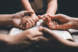 Christian family praying together concept. Child and mother worship God in home. Woman and boy hands praying to god with the bible begging for forgiveness and believe in goodness.