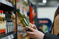 Female hand choosing natural olive oil at store. Concept of healthy food, bio, vegetarian, diet.