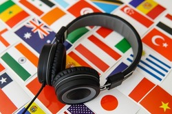 Learning foreign languages online. Headphones and countries flags on the background.