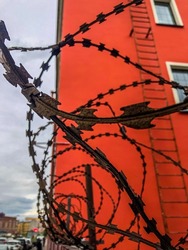 Barbed wire fencing to prevent entry into the protected area. Barbed wire on the background of a red building.