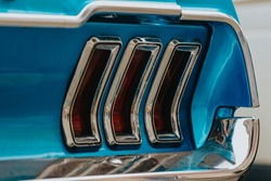 Classic car background. Close-up of the tail light and bumper of classic design, selective background. The concept of restoring old cars. Retro car blue color selective background.