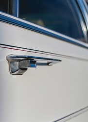 Side view of a shiny white American muscle car with a chrome door handle. The exterior of retro cars.  Side view of the door of a retro car. Vintage, chrome door opening handle.