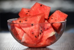 Glassware with juicy and sweet watermelon cubes on a wooden table. Slices of sweet juicy watermelon in a glass plate on a hot summer day.