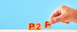 p2p concept. man stacks wooden blocks with the inscription p2p