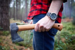 Lumberjack bush crafter holding an axe in the woods in checked shirt.