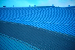 Corrugated metal structure of roof. Abstract architecture of modern hi-tech building. Exterior wall. Closeup photo of minimal industrial real estate object. Geometric pattern of parallel lines.