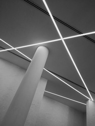 Modern interior fragment in minimalism style. Concrete ceiling with linear daylight lamps. Pillar and plastered walls. Abstract architecture image. Industrial background with geometric structure.