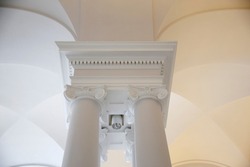 Baroque pillars with Ionic capitals under Gothic arcs. Classical architecture fragment. Architectural detail. Gypsum fretwork. Modern interior in ancient style.