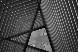 Pitched roof or ceiling. Reworked close-up photo of sloped walls. Realistic though unreal industrial interior. Abstract black and white background image on the subject of modern architecture.