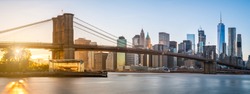 The panorama view of Brooklyn Bridge with Lower Manhattan in the background, lit by sunset