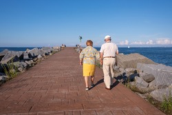 Senior couple walking by the sea, aged people with a healthy lifestyle, long lasting couple holding hands, life expectancy is high in Spain. Mediterranean inspiration, Spain