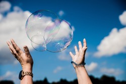 Some one trying to catch soap bubbles. Hands trying to catch  floating soap bubbles