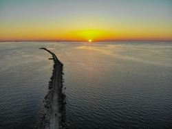 Aerial drone view of a long breakwater and sunset