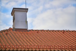 Overlapping rows of red tiles roof with chimneys in Poland, ridge tiling material regular pattern background in horizontal orientation, nobody.