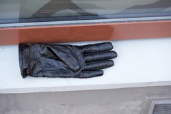 Old black leather gloves lie on a stone