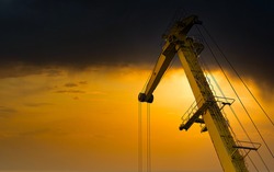 Yellow crane in cargo port translating coal. Industrial scene. Cargo crane at sunset