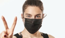 A close-up portrait of a pretty female wearing a surgical mask isolated on a white background