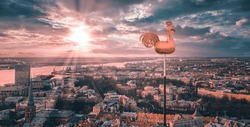 Beautiful aerial view of the city from above with a golden cock in the middle. Sunset time.