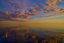 Beautiful sunset over sea with reflection in water, majestic clouds in the sky.