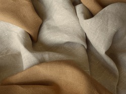 Beige and brown linen fabric. Woven  texture background. Earth tone color textile drapery for sewing, fashion and cloth. Cotton and linen natural textile surface. Beige draped background. 
