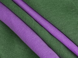 Green and purple draped linen fabric. Woven  texture background. Various colors textile drapery for sewing, fashion and cloth. Cotton and linen natural textile surface. Colorful draped background. 