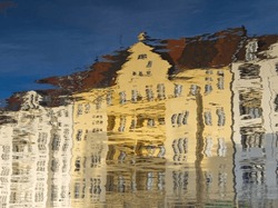 Water reflex background of yellow house. Abstract reflection and abstract inspection elements in water. Buildings, house element distorted in the river. Rippled water texture. Disordered surface. 