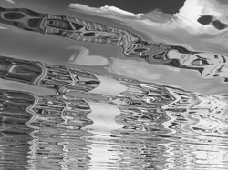 Bw photo of water reflex background. Abstract reflection and inspection elements in water. City, buildings, urban elements distorted in river. Rippled water texture. Disordered black and white surface