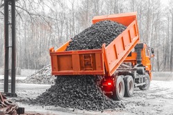 Dump truck in the industrial zone unloads coking coal from the body. Transport coal truck rock stone freight gravel machine mining shovels.