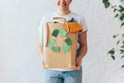 Girl holding paper bag with old clothes for recycling.