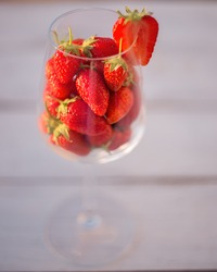 Strawberries in a wine glass on a white wooden background. Fresh strawberry close-up.