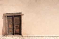 A traditional Omani Arabic wooden door, with solid wall. Copy space. Oman