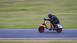 A panning shot of a racing scooter as it circuits a track.