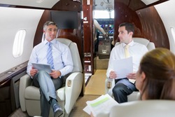 Business employees sitting in a private jet and having a meeting