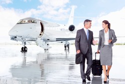 Businesswoman and Businessman talking while walking away from a private jet