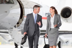 Happy business employees in discussion while walking away from the private jet