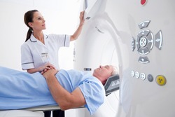 Close up of a nurse operating a CT scan machine while a patient is laying on it