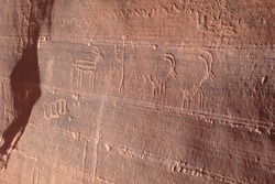 Ancient antelope and human petroglyphs carved on red rock sandstone wall, Navajo Prehistoric Art in Buckskin Gulch canyon, Arizona