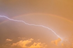 lightning at night in a stormy sky and a rainbow during stormy weather.