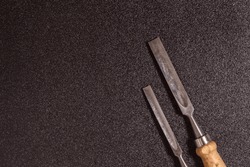 flat lay two wooden-handle chisel on a black speckled background top view