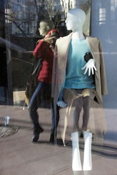 reflection in a shop window of a women's clothing store. Mannequin man photographer is visible with a camera in reflection