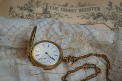Sentimental photo of family items in times past with a family register, handkerchief and pocket watch.