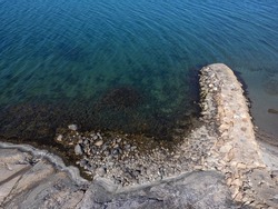 Drone, aerial nature photography, seascape, coastline with cliffs and stone pier in summertime in Sweden.  Blue sea background, copy space with place for text.